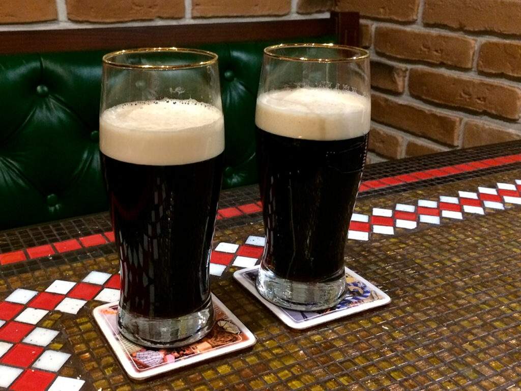 2 glasses of dark Czech Beer on a table